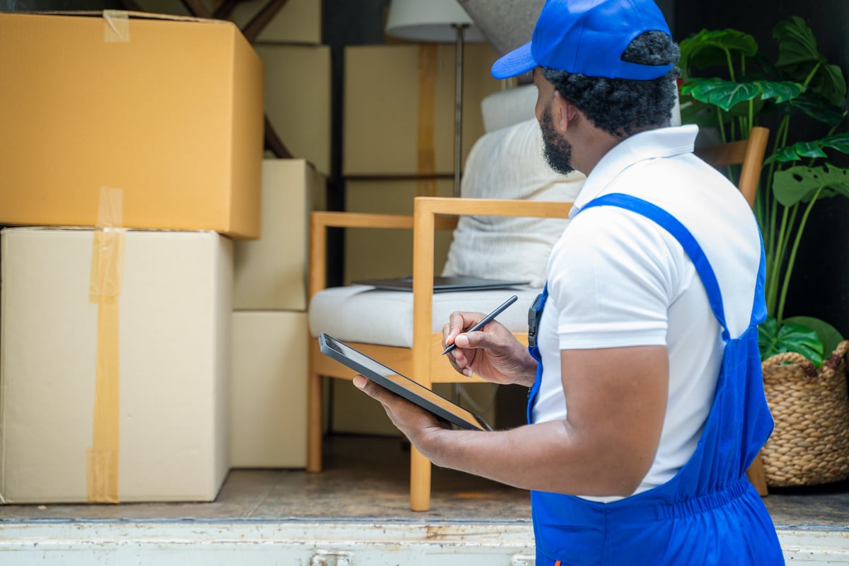 Moving company employee checks boxes in a small truck before sen